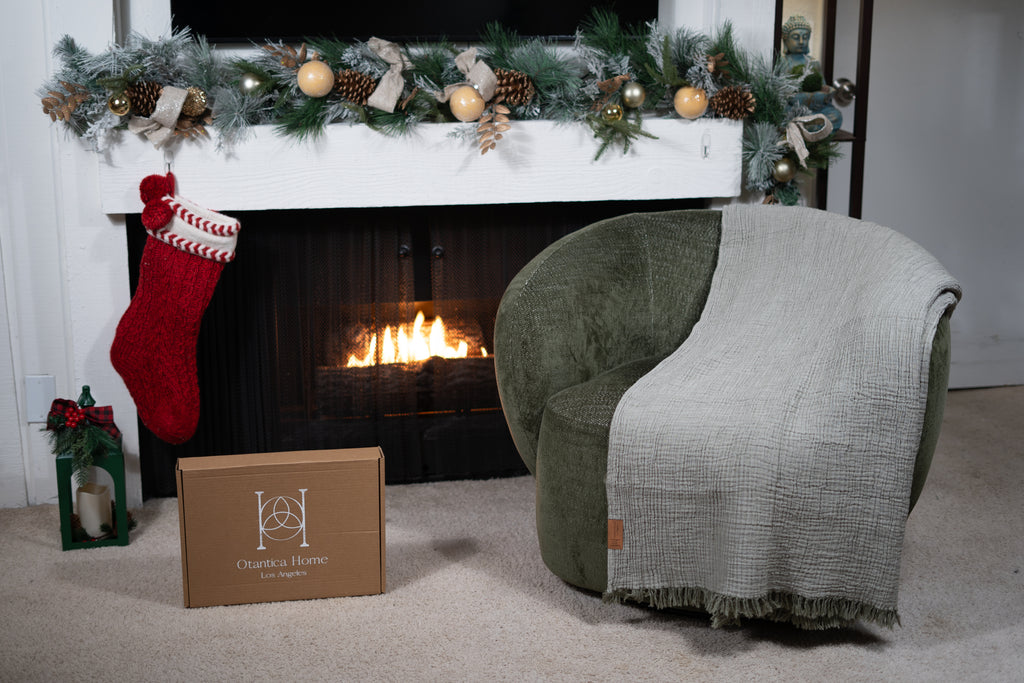 A sage muslin blanket draped over a chair, showing its soft, airy, double-layer muslin texture up close.