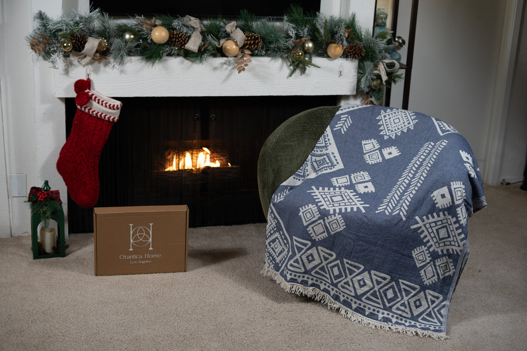 Dark blue organic boho blanket styled over a chair in front of a decorated Christmas fireplace.
