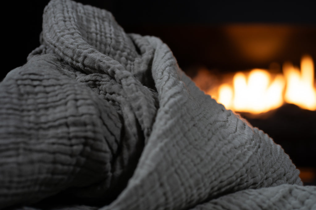 Macro close-up of the grey muslin blanket highlighting its soft, crinkled, double-layer muslin texture.