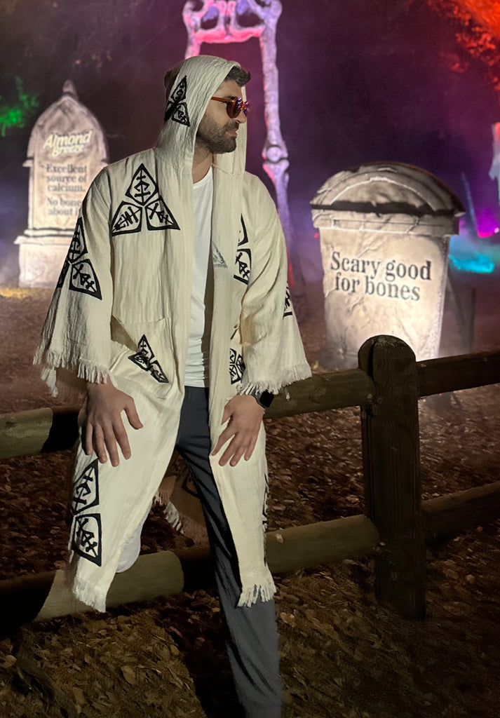 Male model wearing the Veni Vidi Vici hooded kimono in a night festival setting, highlighting the boho aesthetic and organic cotton texture.
