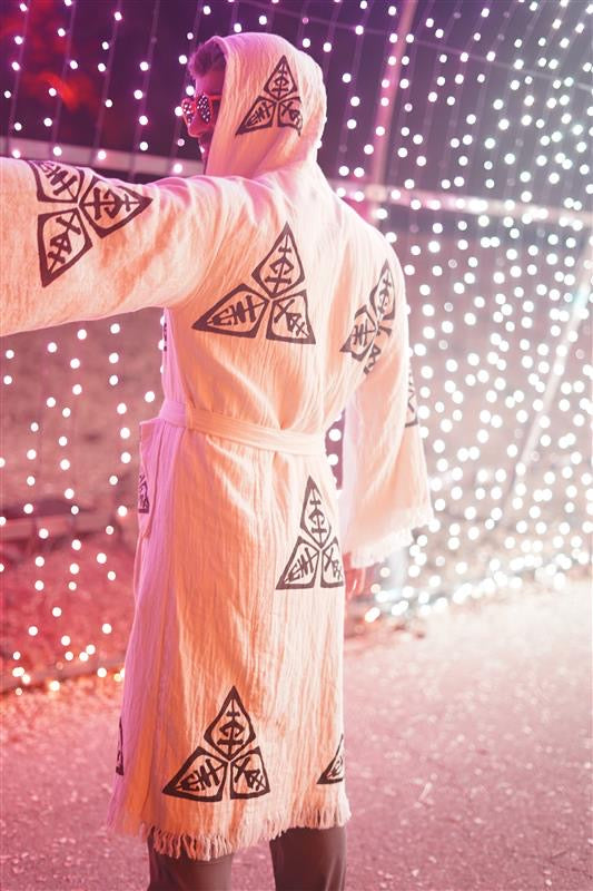 Veni Vidi Vici Kimono photographed outdoors in a colorful festival light installation, showing the flowing unisex fit and bold geometric spiritual motifs.