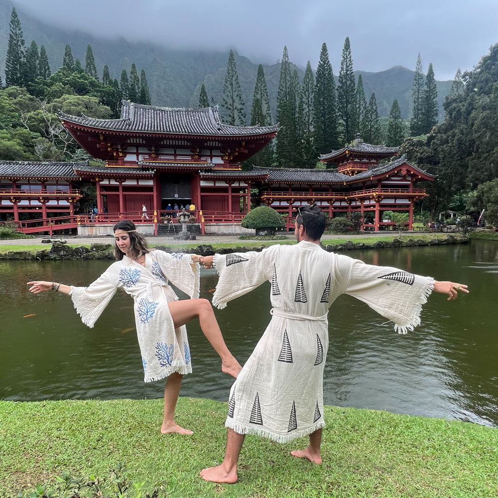 Man and woman wearing tribal kimono and reef kimono, dancing near temple lake in nature