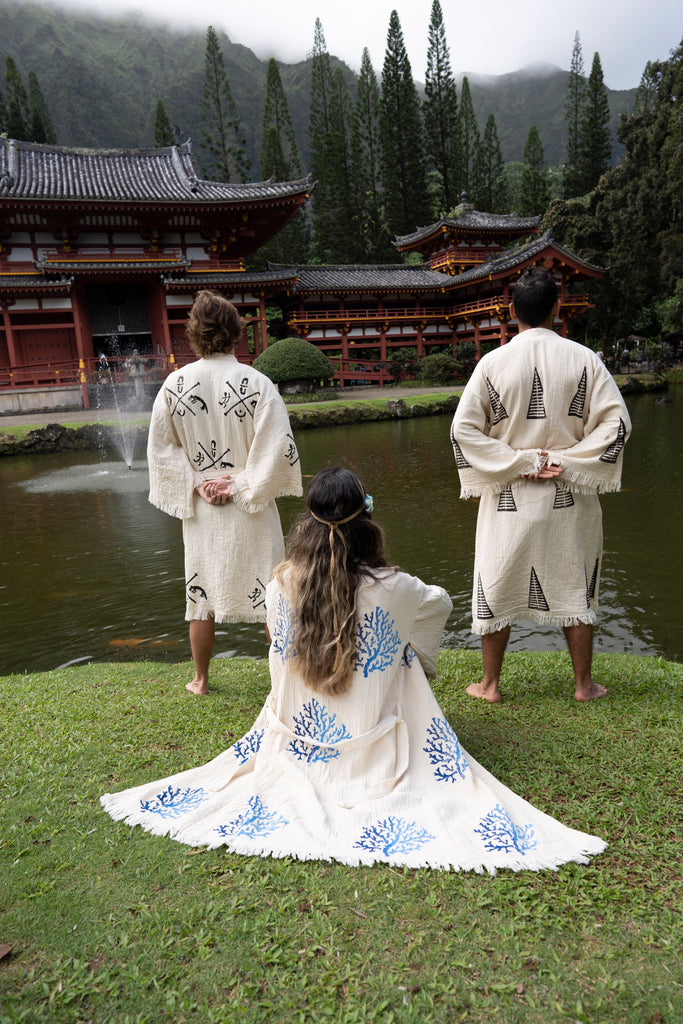 Three people wearing embroidered organic kimonos at a serene temple garden, Reef Kimono displayed in foreground.